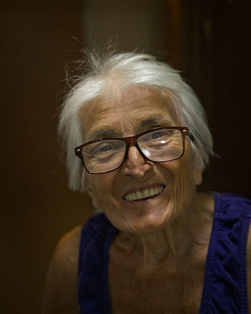 Senhora de cabelos brancos e óculos, sorrindo